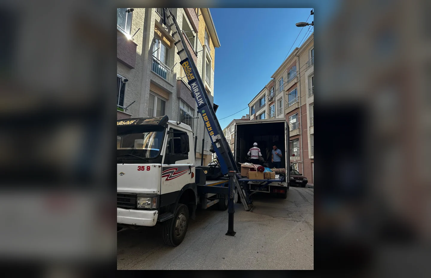 Şehir sokağında iki taşıma aracı ve çalışan dış cephe asansörü